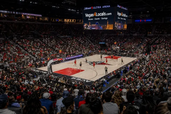 Las Vegas Aces players compete before a large crowd inside Michelob ULTRA Arena as a Vegas4Locals ad appears on the jumbotron.
