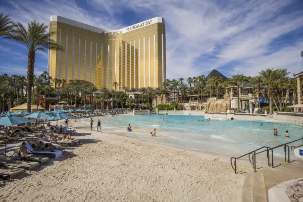Guests relax around the sandy beach, wave pool, and tropical landscaping at Mandalay Bay Beach in Las Vegas.