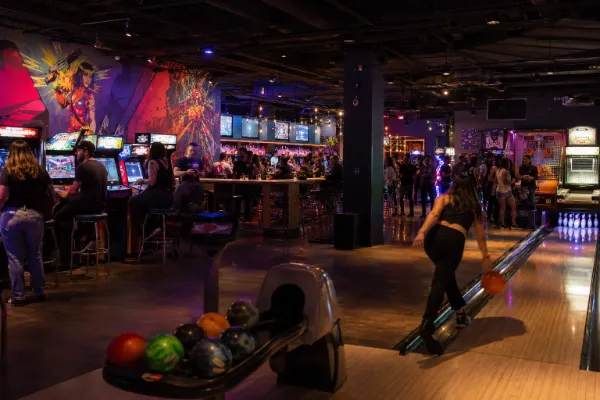Adults enjoy bowling, arcade games, console gaming, drinks, and comic-inspired decor inside The Nerd Las Vegas.