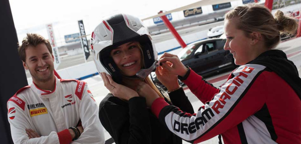 a girl is being helped to get suited up with a helmet before driving at the dream racing las vegas experience