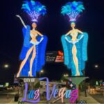 A night time view of two giant LED showgirls near the Downtown Las Vegas Arches