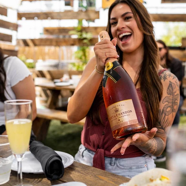 This is a picture of a a girl who holds a bottle of pink champagne during brunch at 18Bin in Las Vegas