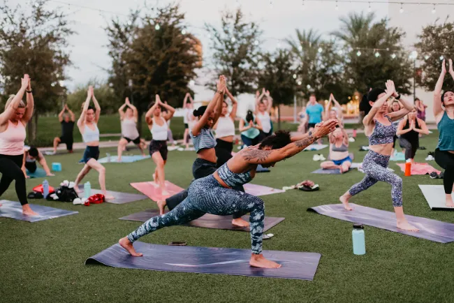This is a picture of people doing yoga stretches at Fitness on the Lawn in Downtown Summerlin