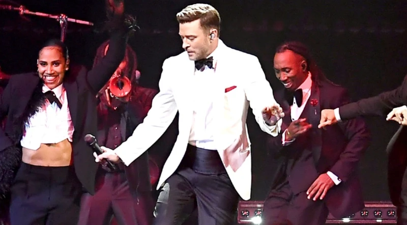 This is a photo of Justin Timberlake in concert dancing with the band