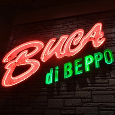 A lit up Buca di Beppo neon lettered sign