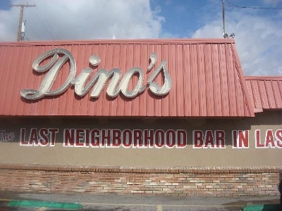 exterior of dinos dive bar on las vegas boulevard with red awning and last neighborhood bar signage