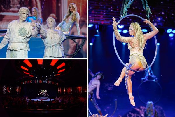 A promotional image for WOW - The Vegas Spectacular, showing a performer on a trapeze above a stage with a water feature, with bright lights behind them.