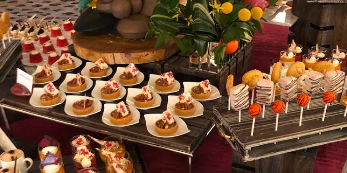 An artistic and luxurious dessert display at the Genting Palace buffet in Resorts World Las Vegas, featuring rows of gourmet tarts, cake pops, and other beautifully arranged pastries.