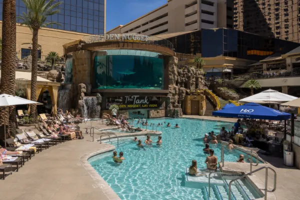 Guests relax around The Tank pool and aquarium structure at Golden Nugget Las Vegas downtown.