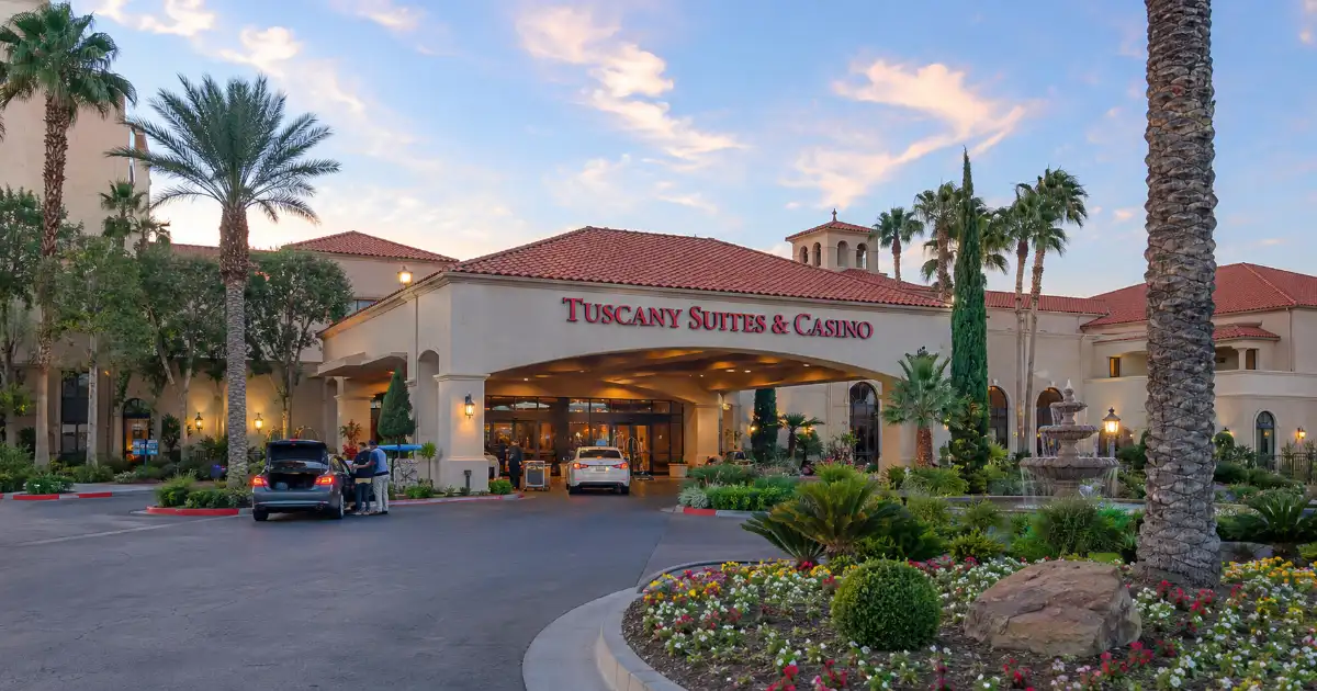 Tuscany Suites & Casino entrance with red-tile roofs, palm trees, and a landscaped driveway in Las Vegas.
