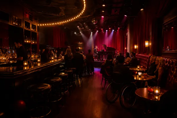 Adult guests watch piano-bar entertainment inside the intimate red and gold Cheapshot showroom on Fremont East.