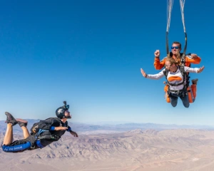 A skydiver takes a tandem jump with an experienced coach and a photographer in Las Vegas