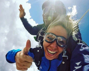 A woman gives a thumbs up while tandem skydiving at the Grand Canyon