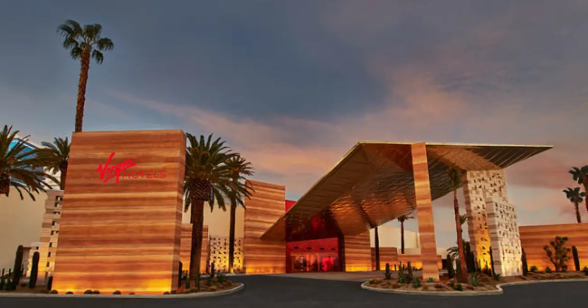 Guests arrive beneath the illuminated entrance of Virgin Hotels Las Vegas as the modern hotel towers rise above Paradise Road.