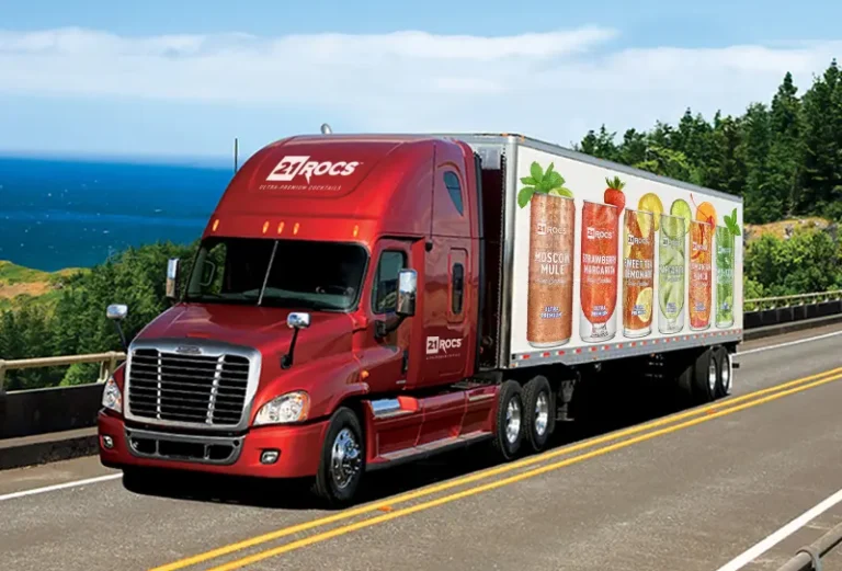 21ROCS delivery truck driving along a coastal highway, showcasing vibrant images of all six Ultra-Premium Canned Cocktail flavors on the side of the truck.
