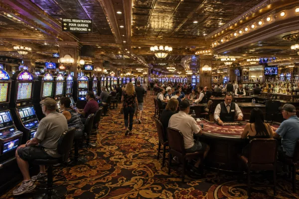 Adult guests play slots and table games beneath ornate lighting inside Four Queens Hotel & Casino in downtown Las Vegas.