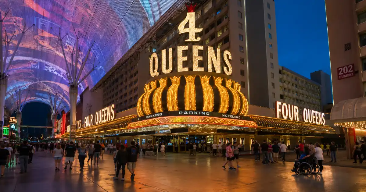 Visitors walk beneath the Fremont Street Experience canopy outside the illuminated Four Queens Hotel & Casino in downtown Las Vegas.