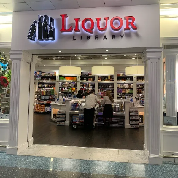 Exterior entrance of Liquor Library at McCarran International Airport in Las Vegas, Nevada. Bold signage with “LIQUOR LIBRARY” in red and black lettering highlights the store’s curated selection of wines and spirits. Inside, sleek shelving displays a variety of liquor bottles under bright lighting, creating a stylish and accessible stop for wine tasting enthusiasts arriving in Las Vegas. A unique airport wine experience that blends convenience with local flavor.