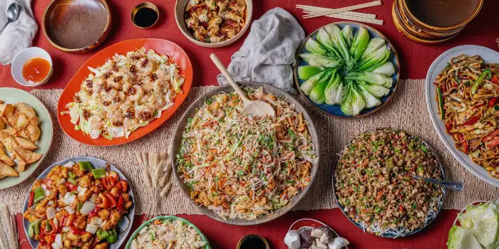 A large table with a variety of Chinese dishes, including fried rice, stir-fried noodles, seafood salad, and dumplings, representing the all-you-can-eat offerings at Chin Chin Buffet in the New York-New York Hotel.