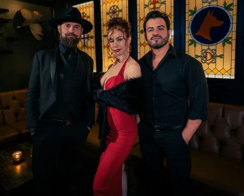 Cabaret trio from Keys to Doberman at Doberman Drawing House in downtown Las Vegas, posing in front of a dog-themed stained glass window.