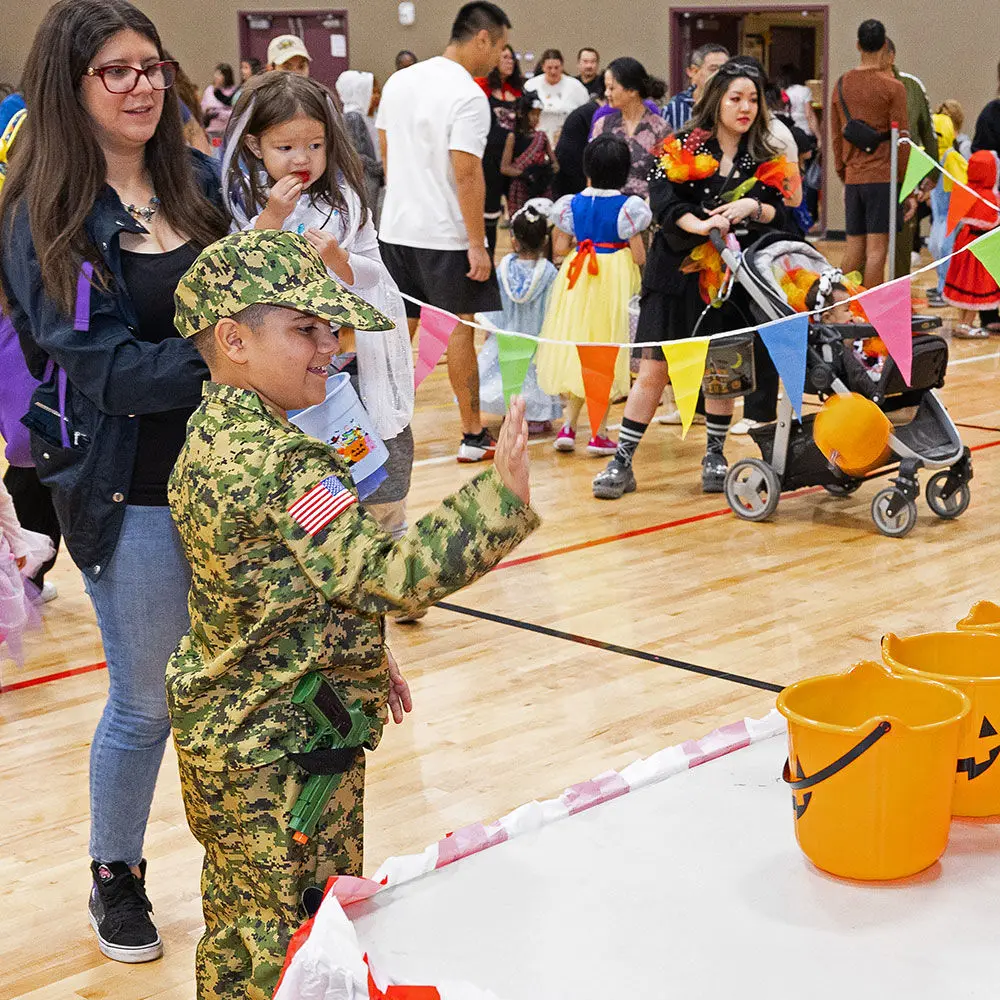 A boy in military fatigues points at a jack o'lantern