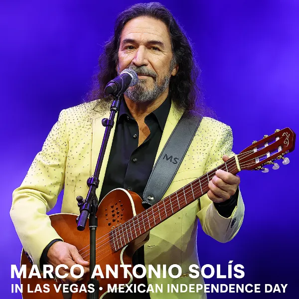 Marco Antonio Solís performing live in Las Vegas for Mexican Independence Day 2025, wearing a rhinestone-studded jacket and playing acoustic guitar under vibrant purple stage lighting.