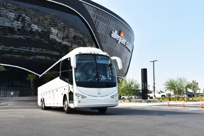 TLC Transportation white tour bus driving past Allegiant Stadium in Las Vegas