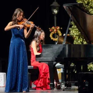 young musicians performing violin and piano at youth for youth holiday concert in las vegas 2025 with festive christmas decorations supporting the just one project