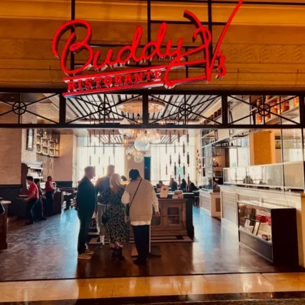Entrance to Buddy Vs Ristorante at The Venetian Las Vegas with red neon sign chandeliers and guests waiting to be seated