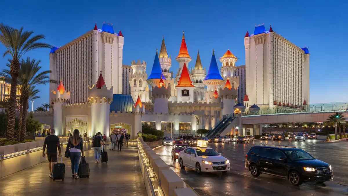 Guests arrive at the illuminated castle façade and towers of Excalibur Hotel & Casino on the Las Vegas Strip at twilight.
