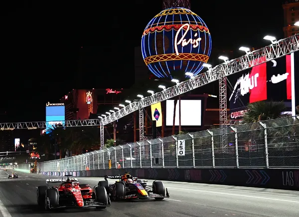 Formula One Grand Prix race in Las Vegas with Ferrari and Red Bull cars side by side on illuminated street circuit near Paris Las Vegas Hotel
