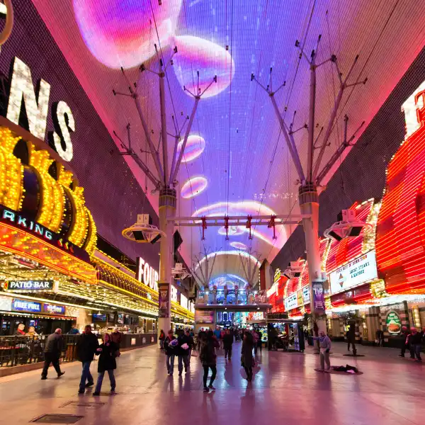 pedestrians walking under vibrant led canopy at fremont street experience in downtown las vegas with four queens casino and patio bar illuminated