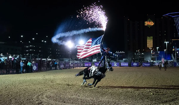 Helldorado Days Rodeo in Las Vegas with horseback rider carrying American flag under fireworks at night in fall season