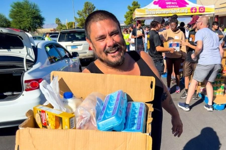 man holding grocery box at just one project mobile food bank event with volunteers and banner in las vegas