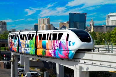 Las Vegas Monorail with colorful wrap and social media icons traveling on elevated track with city skyline and hotels in background