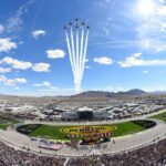 Las Vegas Motor Speedway during Pennzoil 400 NASCAR race with packed stands, race cars on track, and fighter jet flyover