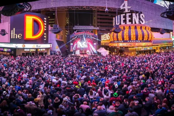 massive crowd celebrating new years eve at fremont street experience in downtown las vegas with live concert stage and casino lights