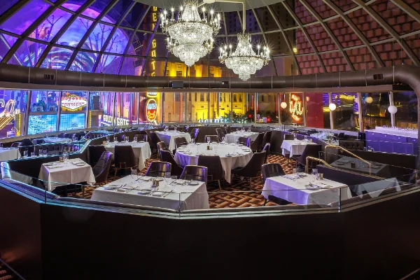 elegant dining room at oscars steakhouse in downtown las vegas with white tablecloths chandeliers and city views through glass dome at plaza hotel