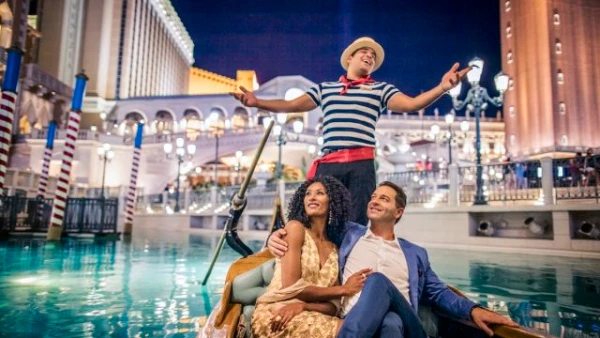 Outdoor gondola ride at The Venetian Las Vegas with singing gondolier romantic couple and Venetian style architecture