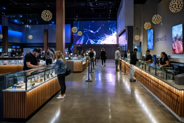 Adult customers browse illuminated displays and interactive digital features inside the modern Planet 13 Las Vegas cannabis dispensary.