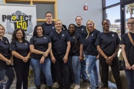 group of project 150 volunteers posing indoors with banner supporting homeless and disadvantaged high school students in las vegas