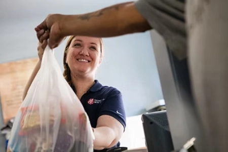 woman receiving food bag from salvation army volunteer in las vegas community assistance program