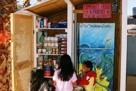 children exploring solidarity fridge community pantry in east las vegas with mural and stocked shelves of free food