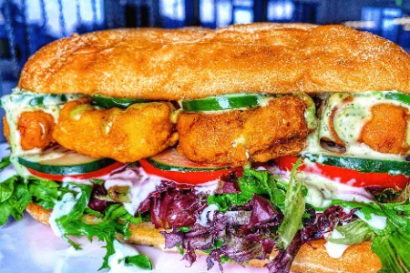 vegan sandwich with fried filling cucumber tomato greens and herb sauce at the modern vegan in las vegas