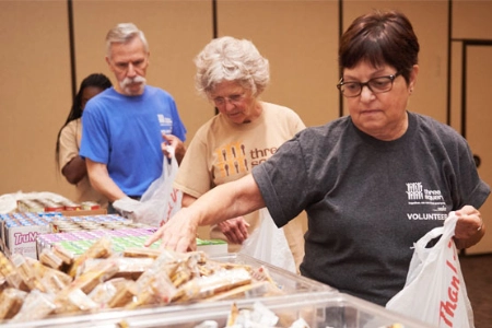 volunteers packing food bags at three square food bank pantry event with snacks and supplies in las vegas