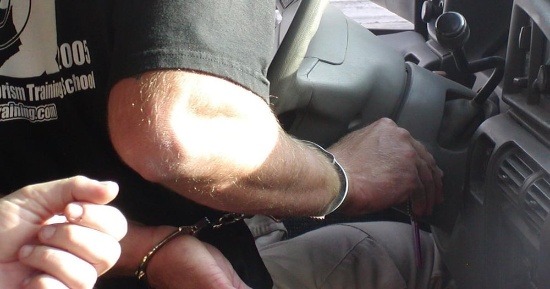 Two individuals in handcuffs seated inside vehicle during prison training simulation for Vegas Tactical Adventures in Las Vegas