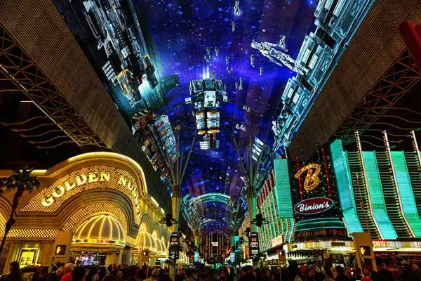 crowd watching viva vision light show under massive led canopy at fremont street experience in downtown las vegas with golden nugget and binions casinos lit up
