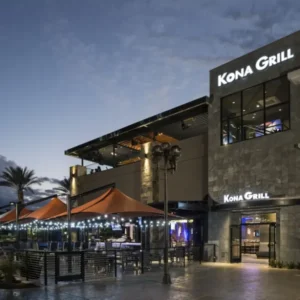 kona grill restaurant at boca park las vegas with illuminated signage outdoor seating and orange umbrellas at dusk