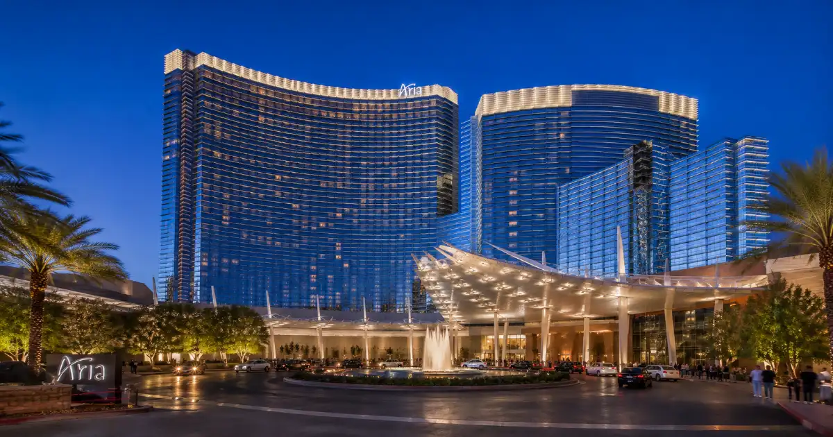 The curved glass towers, entrance canopy, fountain, and landscaped arrival drive at ARIA Resort & Casino in Las Vegas.