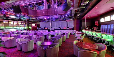 interior of the back door gay bar in las vegas with lounge seating purple lighting and stage for drag shows